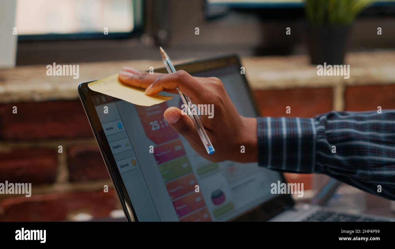 Employee putting sticky notes on laptop screen as work reminder in ...