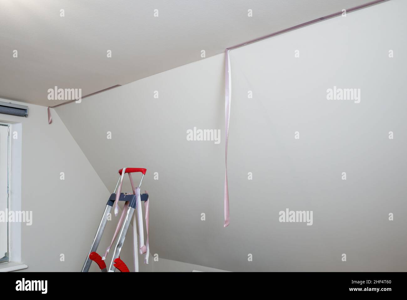 Removal of purple scotch tape from the ceiling after painting the walls with the help of a ladder Stock Photo