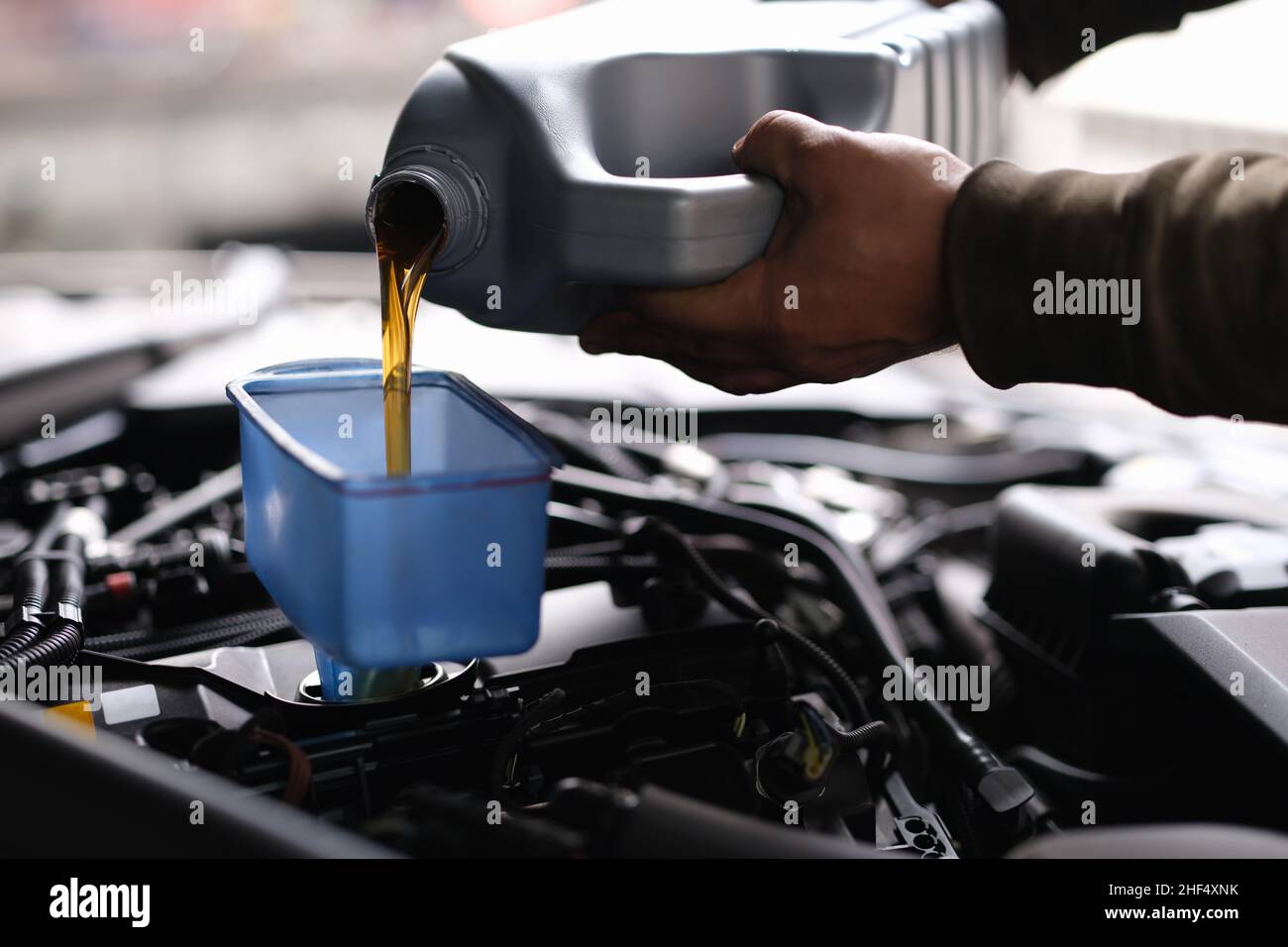 Male hands pouring machine oil through funnel into car engine Stock