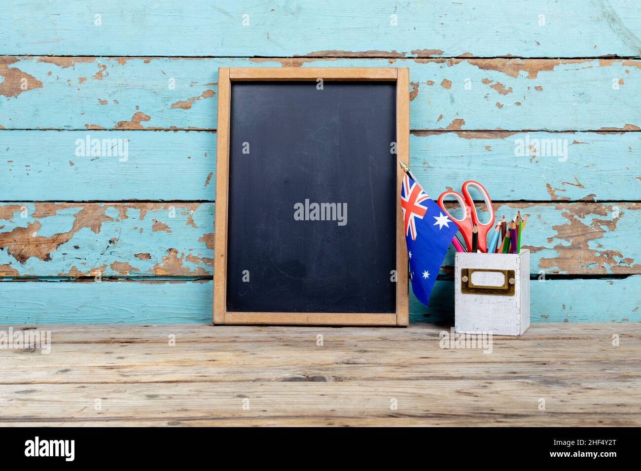 Blank writing slate by australian flag and desk organizer against wooden wall with copy space Stock Photo