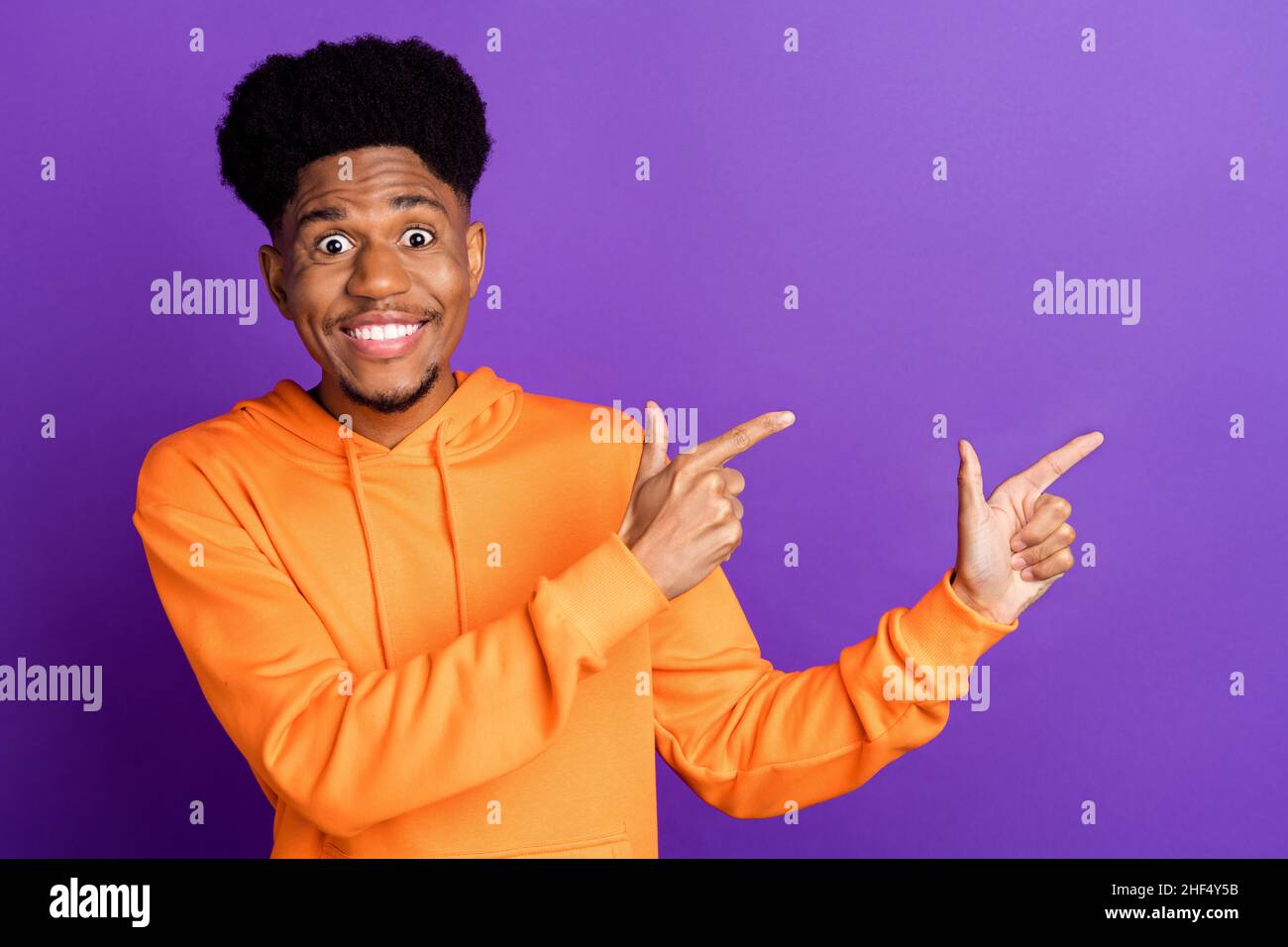 Photo of positive happy dark skin young man point fingers empty space ...