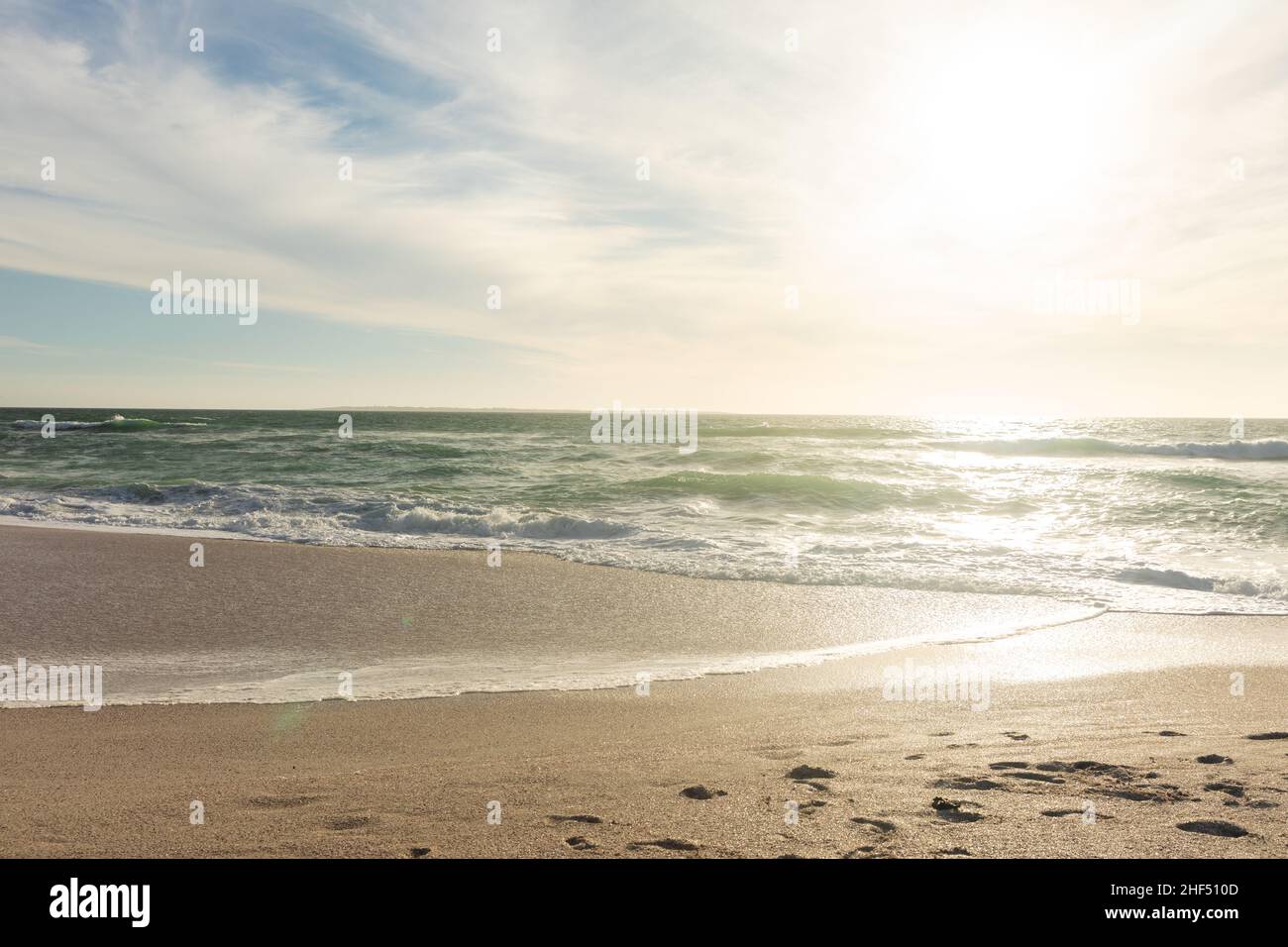 Scenic view of waves on shore at beach against sky during sunny day Stock Photo