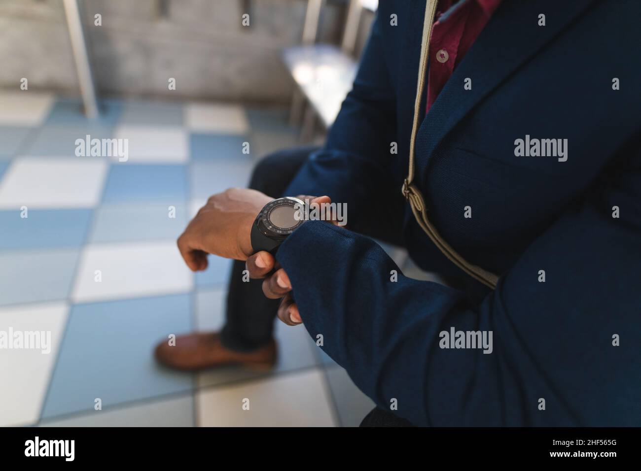 Mid section of businessman using smartwatch while sitting at the bus stop on the go to office Stock Photo