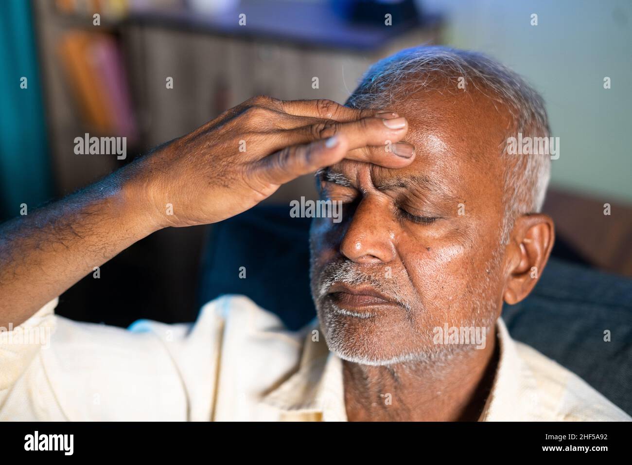Senior man suffering from headache - concept of stress, family problems and illness during coronavirus covid-19 lockdown. Stock Photo