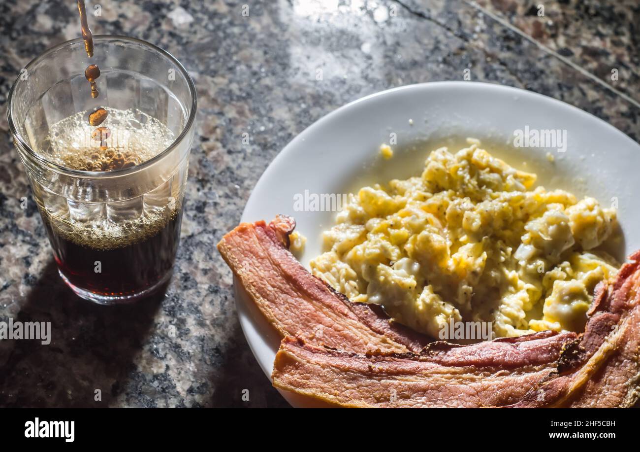sliced bacon on a plate with scrambled eggs and a cup of coffee on the ...