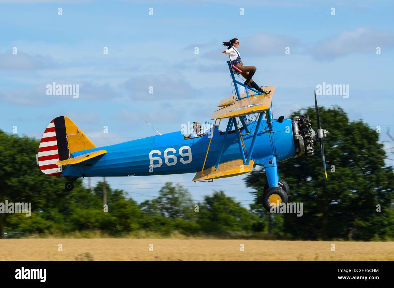 Sarah Niles wingwalking on a Boeing Stearman plane at Damyns Hall Aerodrome with Aerobatic Tactics. Girl on the wing, wing walking. Close to ground Stock Photo