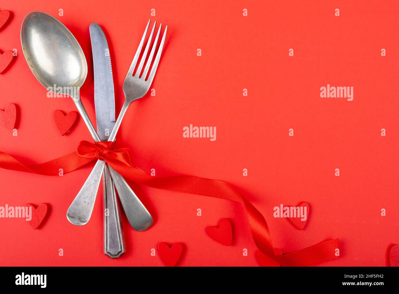 Overhead view of cutlery tied with ribbon over red background with copy space Stock Photo