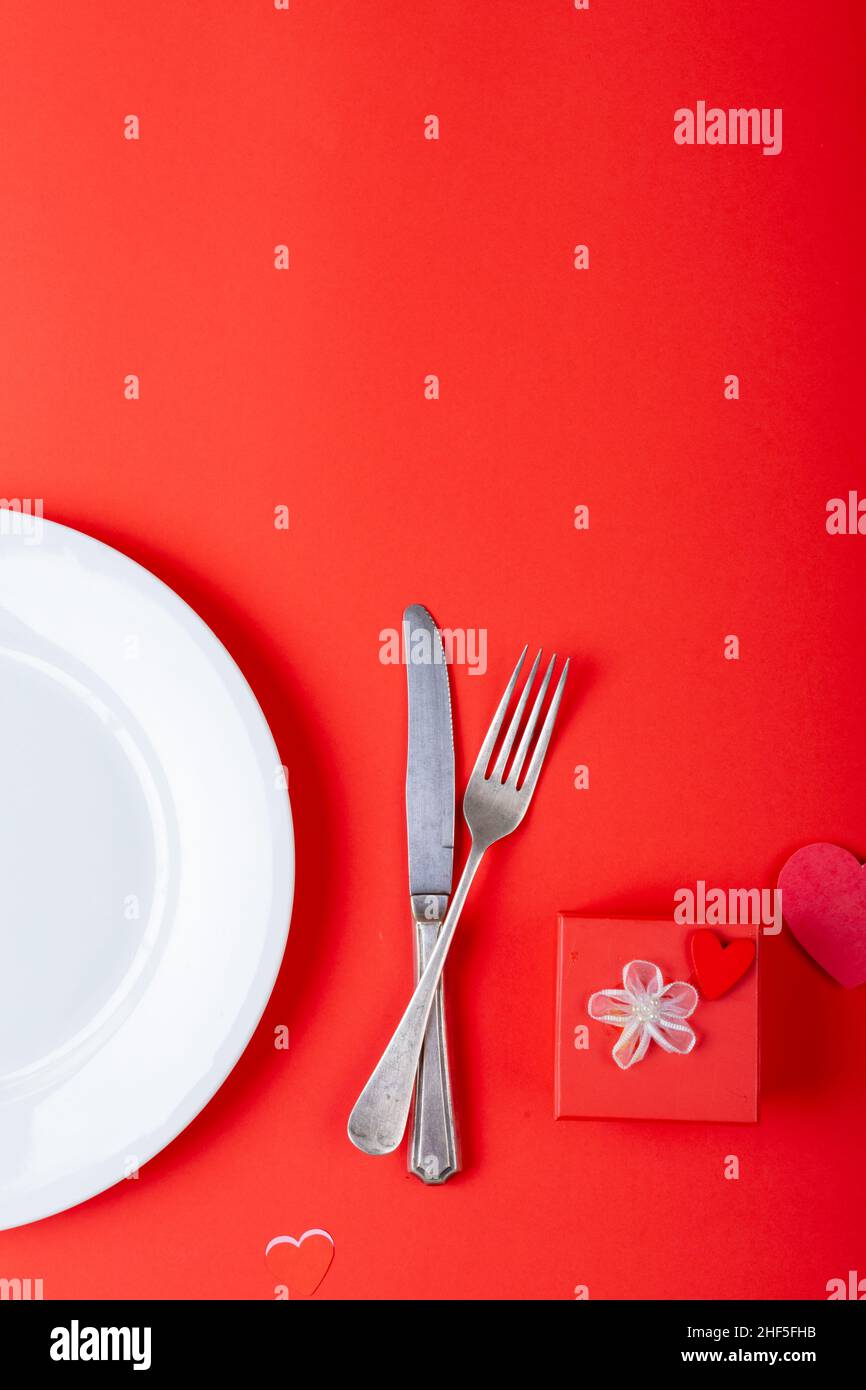 Overhead view of place setting by valentine gift on red background, copy space Stock Photo