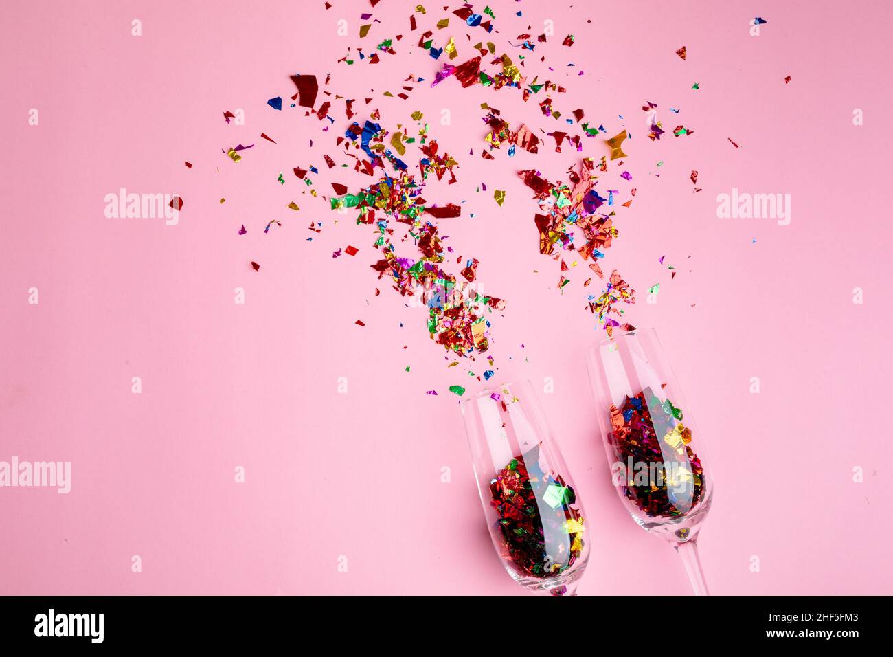 https://c8.alamy.com/comp/2HF5FM3/multi-colored-confetti-and-champagne-flutes-isolated-against-pink-background-copy-space-2HF5FM3.jpg