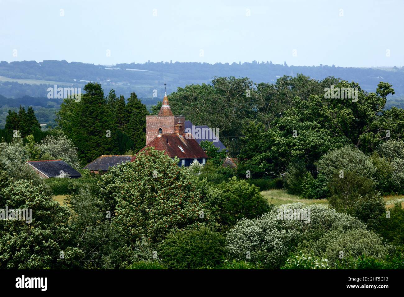 View of All Saints church in Tudeley village and surrounding countryside in early summer, seen from the High Weald Walk footpath, Kent, England Stock Photo
