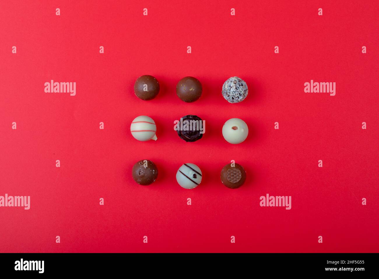 Overhead view of different chocolate spheres arranged on red background with copy space Stock Photo