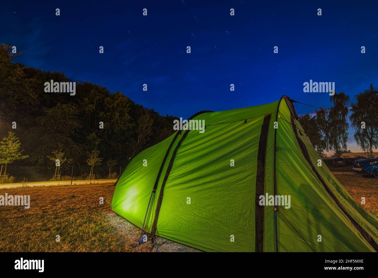 Adventure and outdoor activities: illustration for camping in a meadow, lawn or clearing underneath the stars at night with a big green tent in Sweden Stock Photo