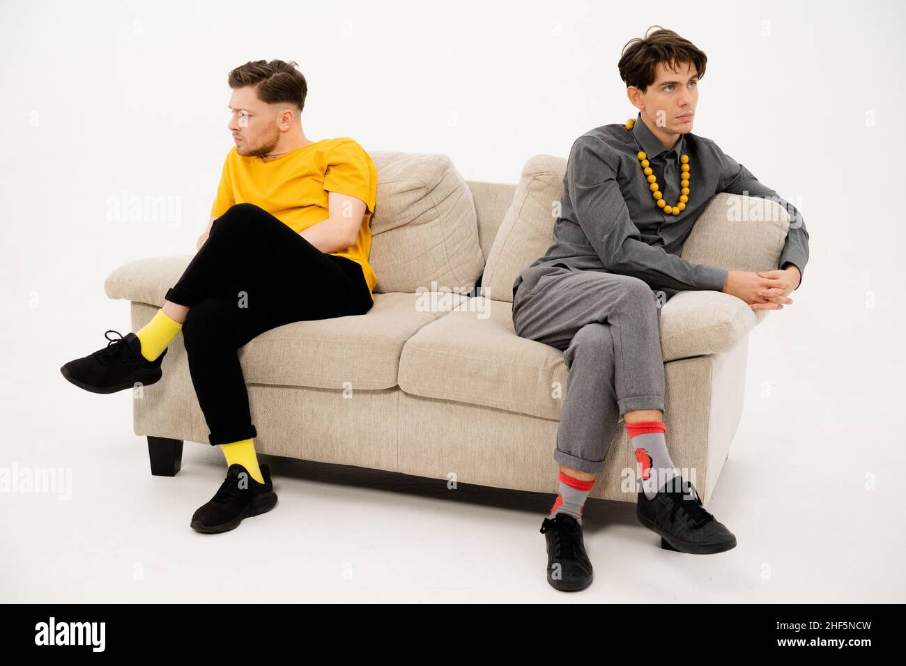 Two Friends Quarreled and Sat on Opposite Sides of the Sofa. Men are in a Quarrel and sit on the Couch at a Distance from Each Other. Close-up. High quality photo Stock Photo