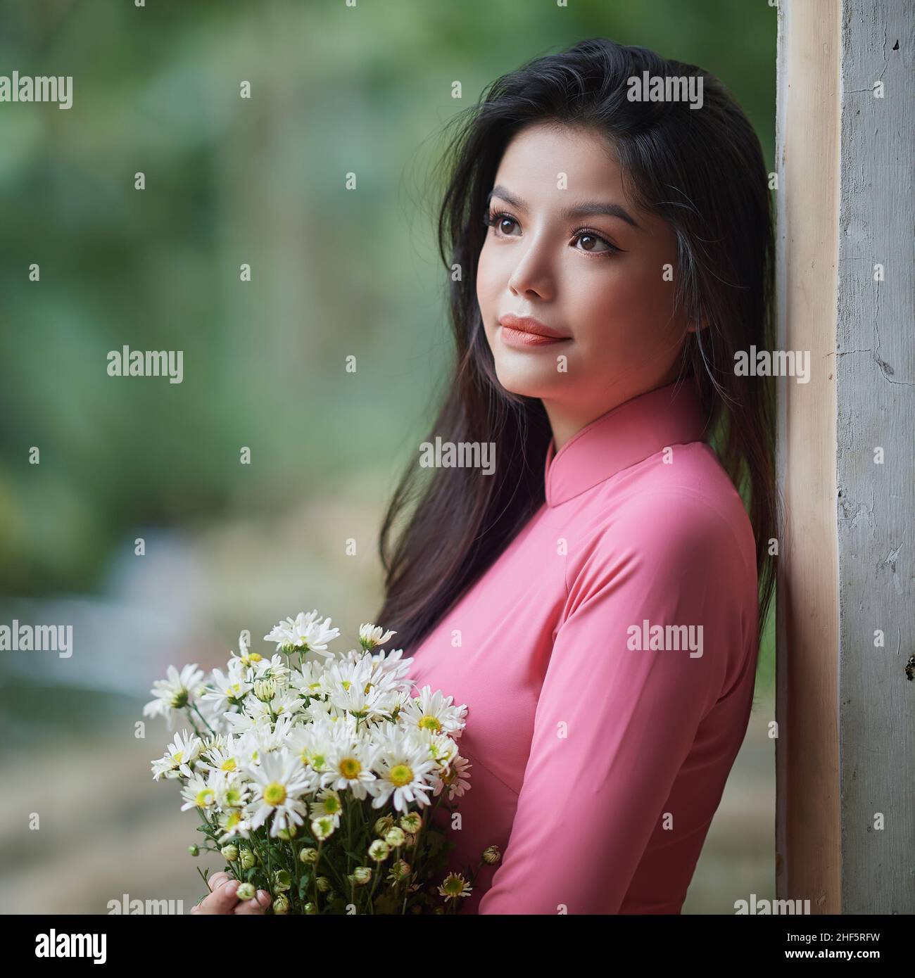 Ho Chi Minh City, Vietnam: Charming Vietnamese woman in ao dai, taking pictures with chrysanthemums Stock Photo