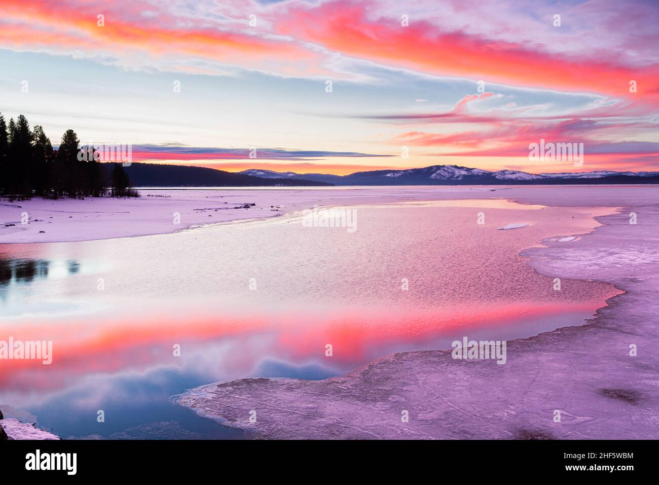 Vibrant sunrise reflecting off open water amid ice.  Photoraphed at Lake Almanor in Plumas County, California, USA. Stock Photo