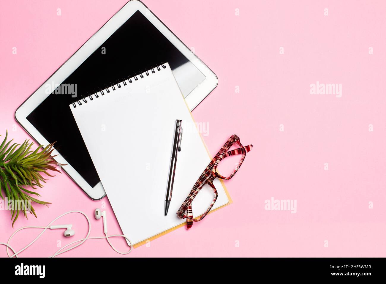 Digital tablet, notepad and a pen on a pink background with copy space Stock Photo