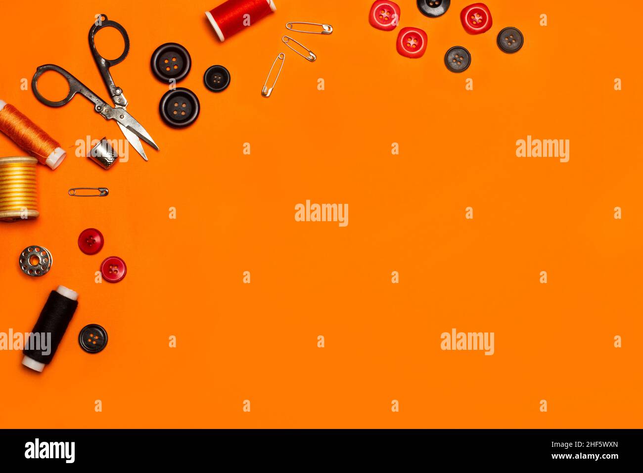 Scissors, sewing thread, colored buttons and sewing accessories on an orange background Stock Photo
