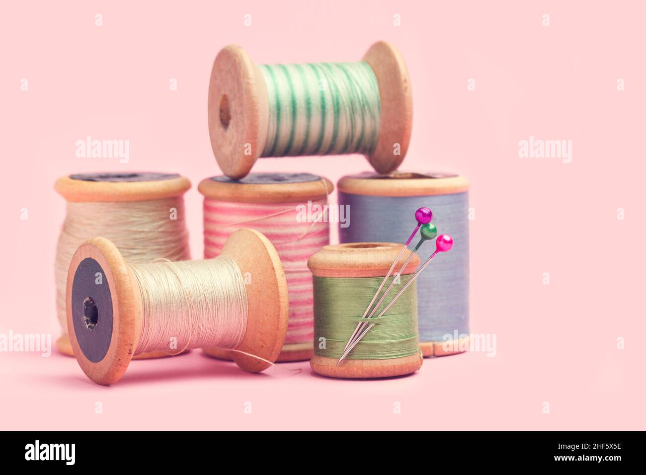 Colored thread spools on a pink background Stock Photo