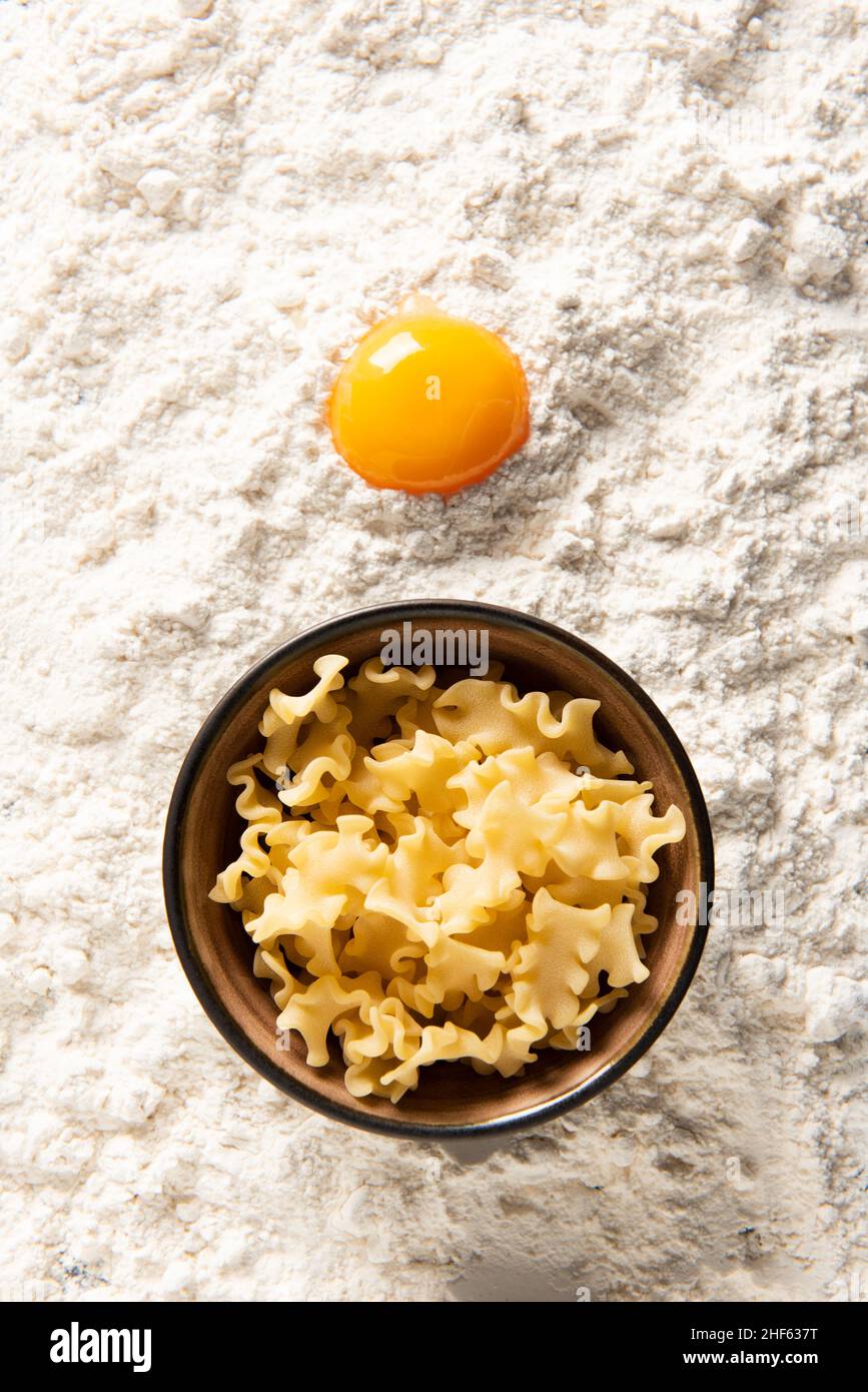 Bowl of pasta and egg yolk on flour. Stock Photo