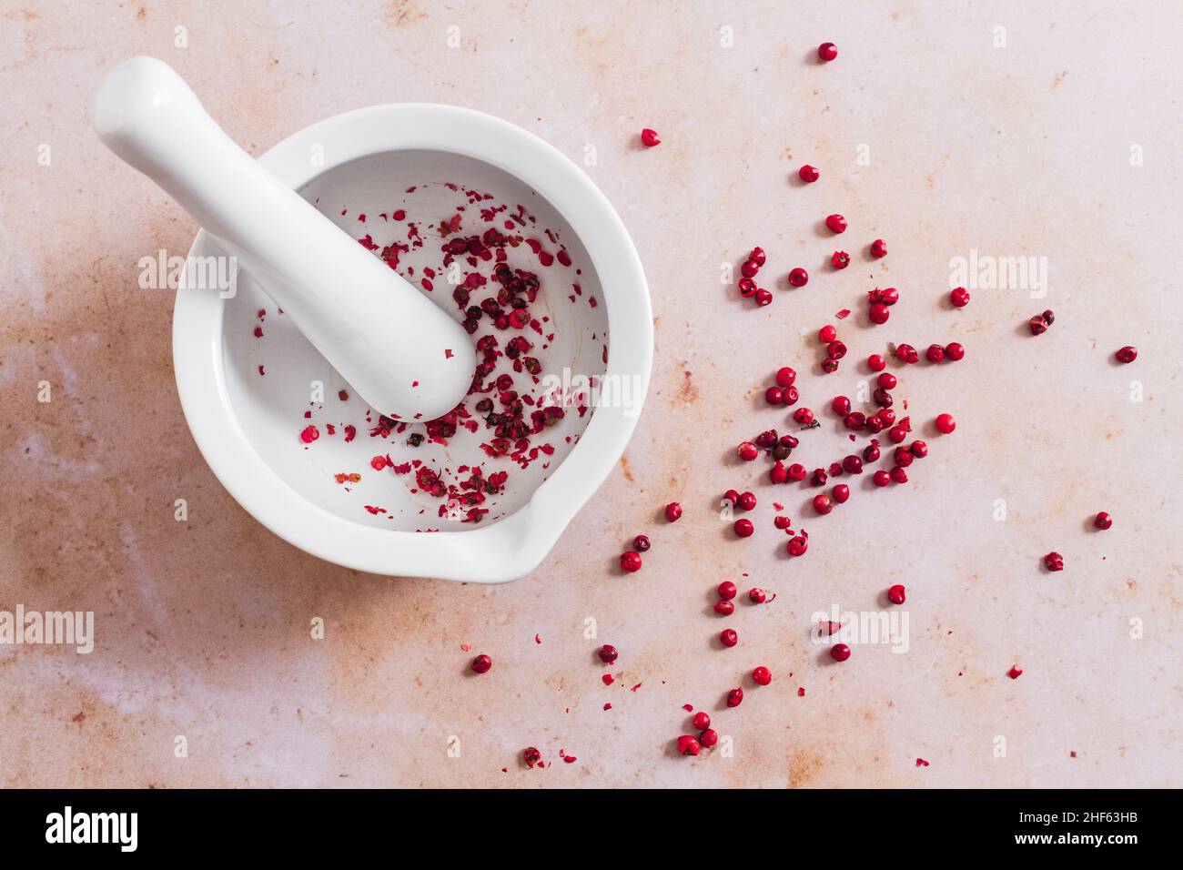 White pestle and mortar with pink peppercorn. Stock Photo