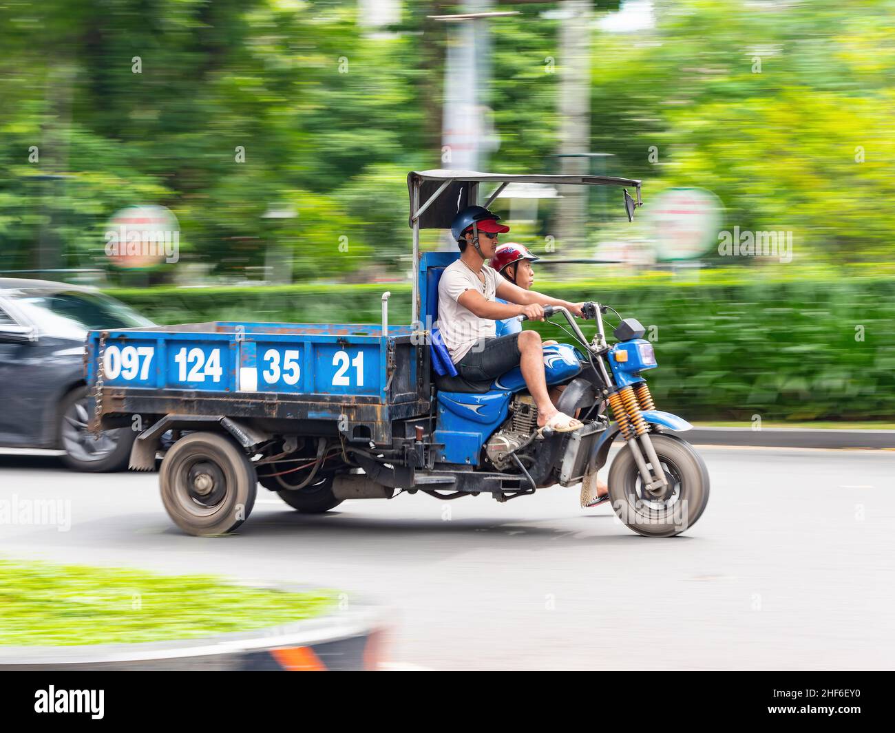 Motorcycle based truck at speed in Ho Chi Minh City, Vietnam. The photo has motion blur, with the driver sharp in focus. Stock Photo
