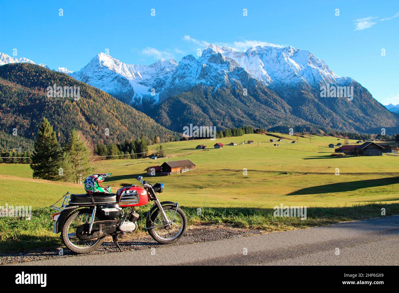 A motorcycle stands on a field path between Krün and Mittenwald in front of  the alpine backdrop of the freshly snow-covered Karwendel Mountains. DKW  139S, built in 07/1969, Zweirad Union, Bavaria, Germany