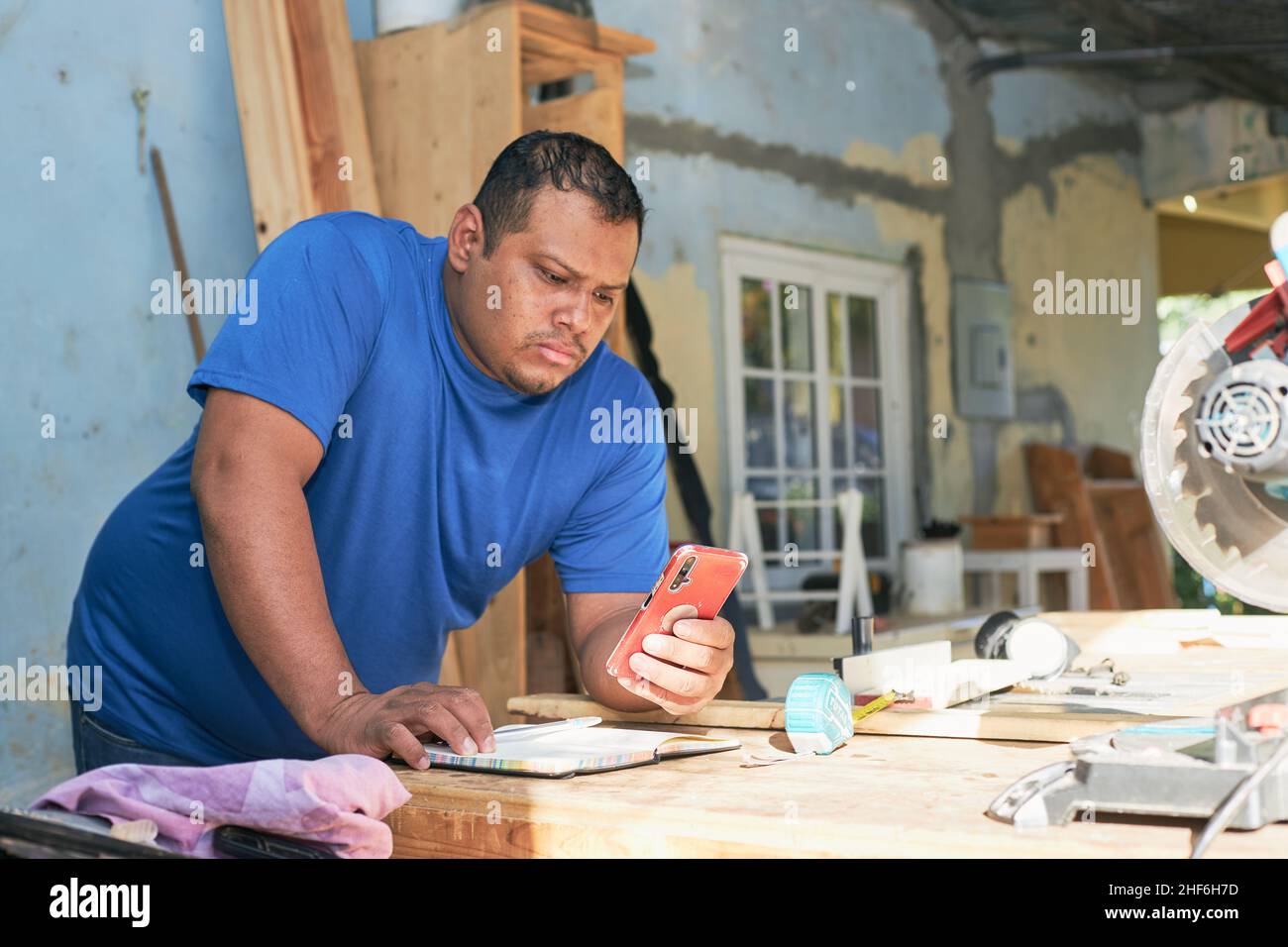 latin man checking orders on cell phone Stock Photo