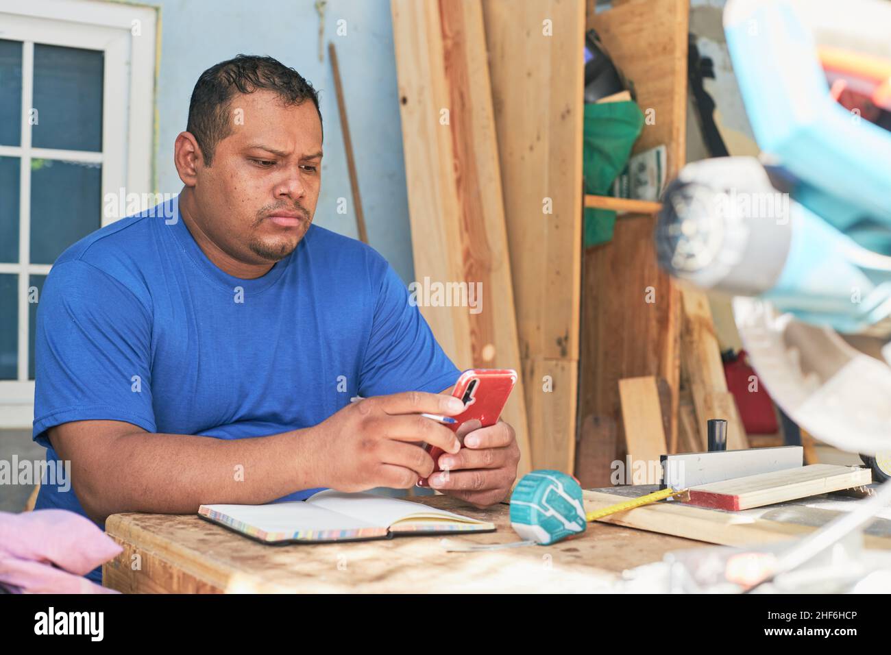 latin man checking orders on cell phone Stock Photo