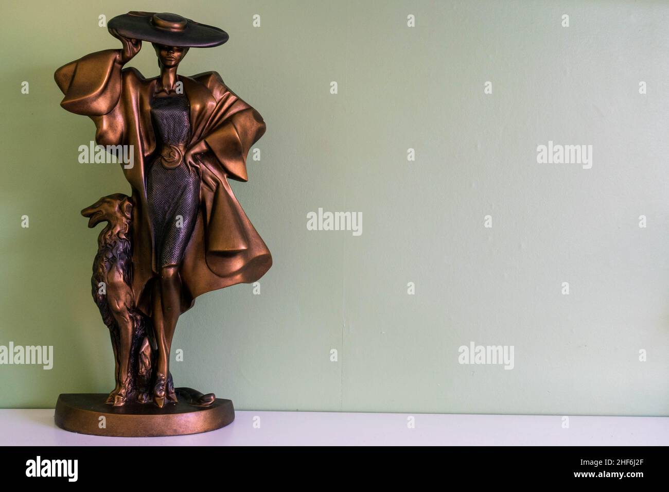 Hull, UK - 25th August 2019: Posh classy lady with large hat and dog home décor ornament. Unique bronze metal statue conceptualising modern vintage Stock Photo