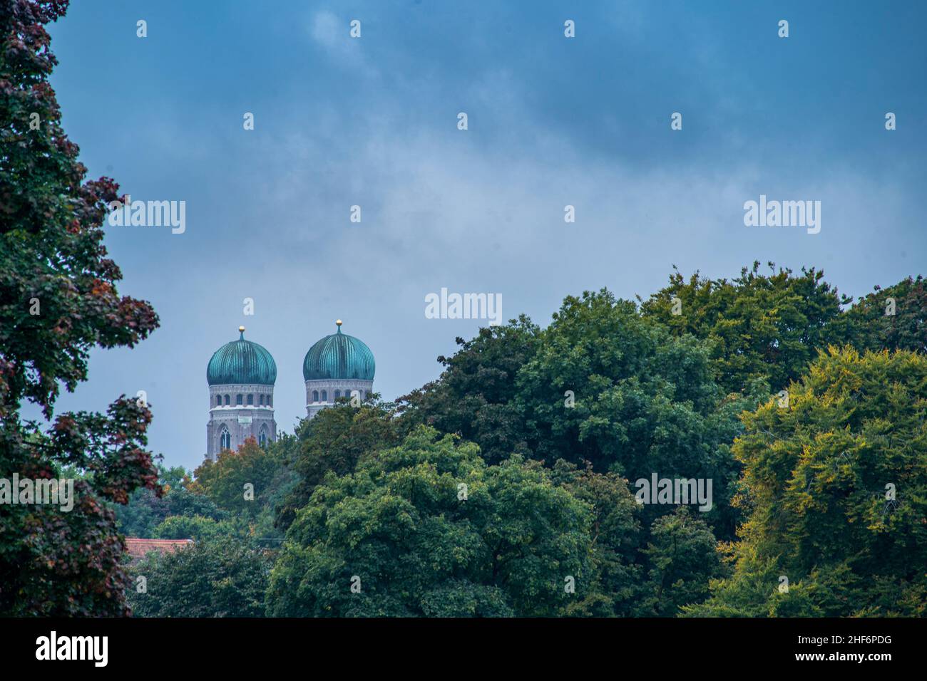 View at the tops of the both popular towers of the Frauenkirche in Munich,  bavaria over green and autumn colored treetops Stock Photo