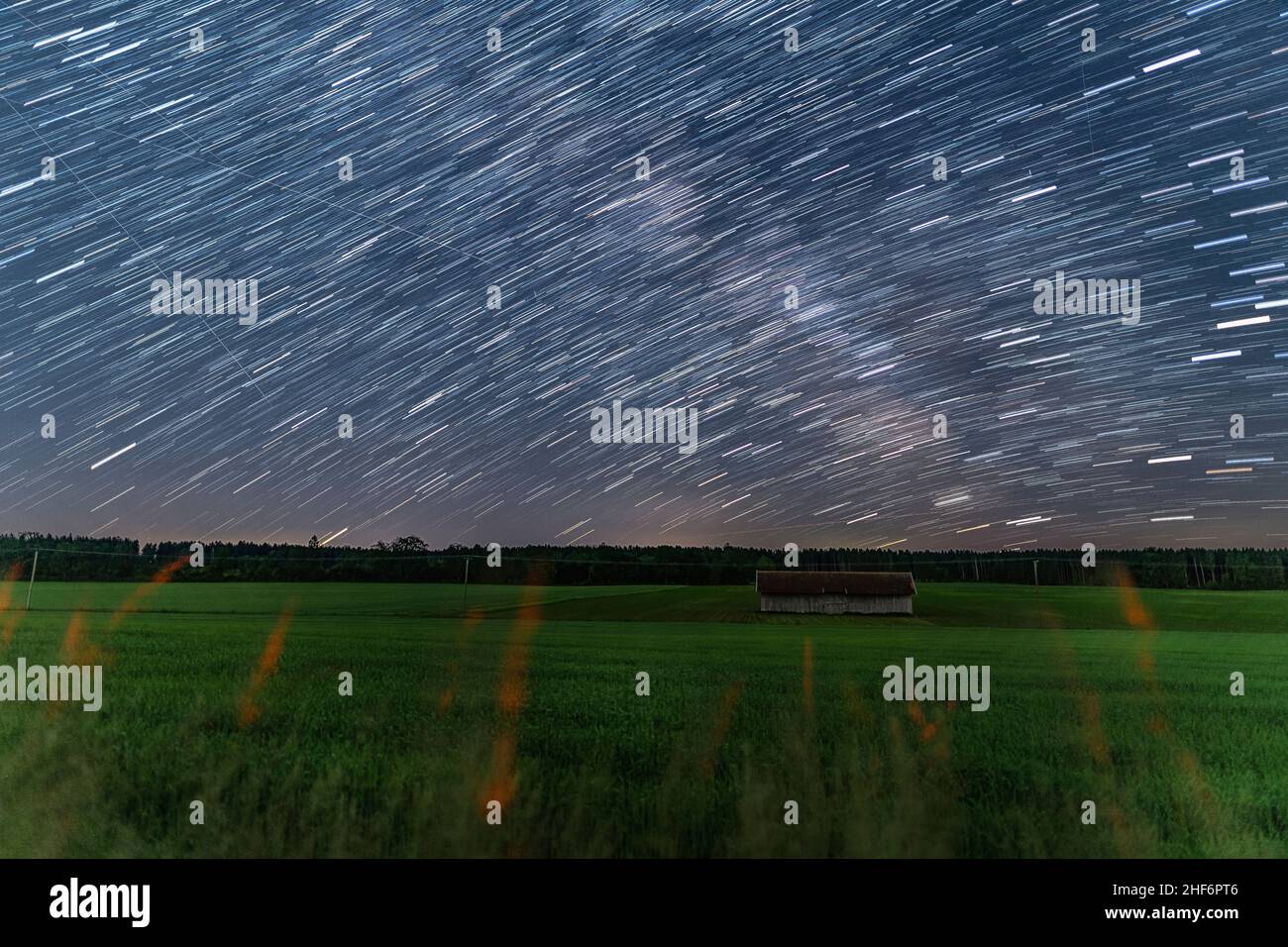 Startrails over a little hut at a farmland at the starry night,  beautiful nature and concept for motion of the earth Stock Photo