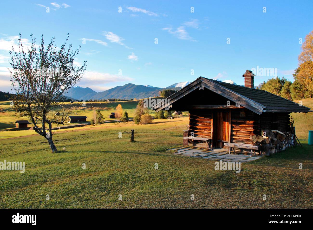 Hut in the humpback meadows near Mittenwald,  trees,  white-blue sky,  mountains in the background,  harmonious Stock Photo
