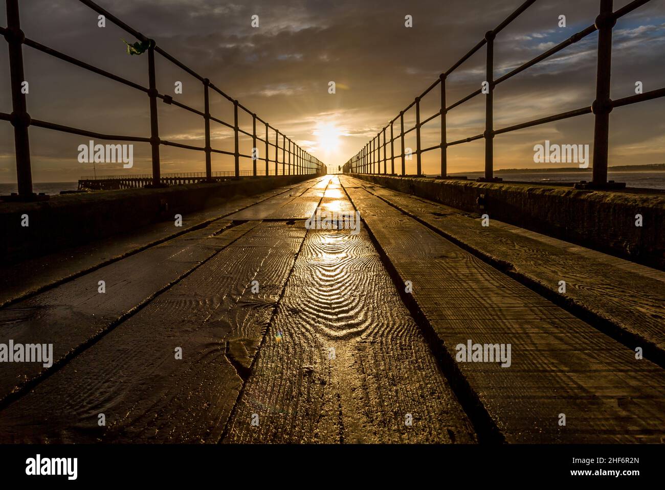 A close-up of a textured wooden plank on the old wooden Pier stretching out to the North Sea during a glorious morning at Blyth beach Stock Photo
