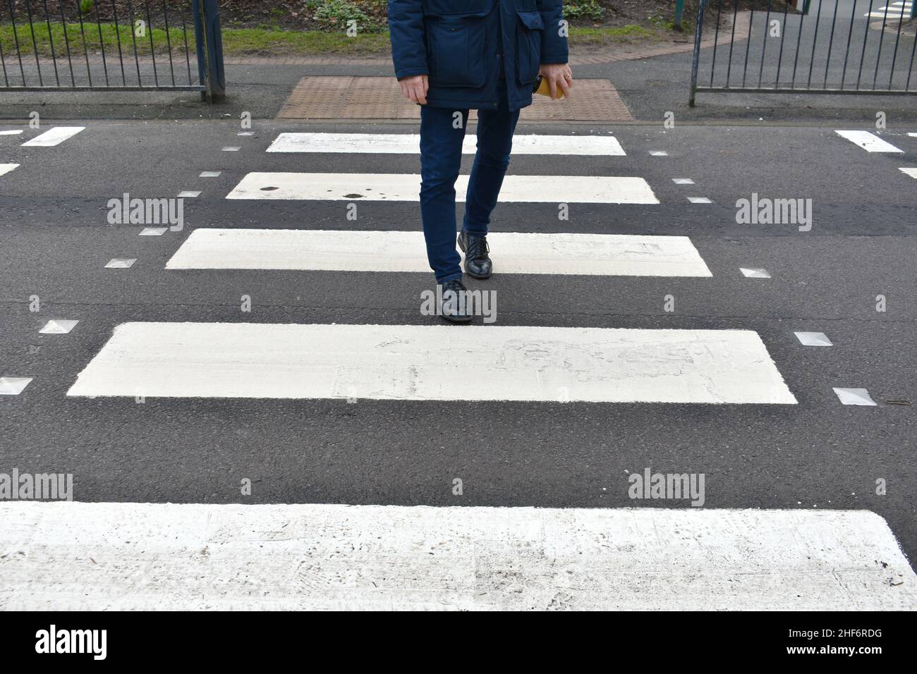 close up of mans feet and legs, walking along a zebra crossing, crossing the road, outside a