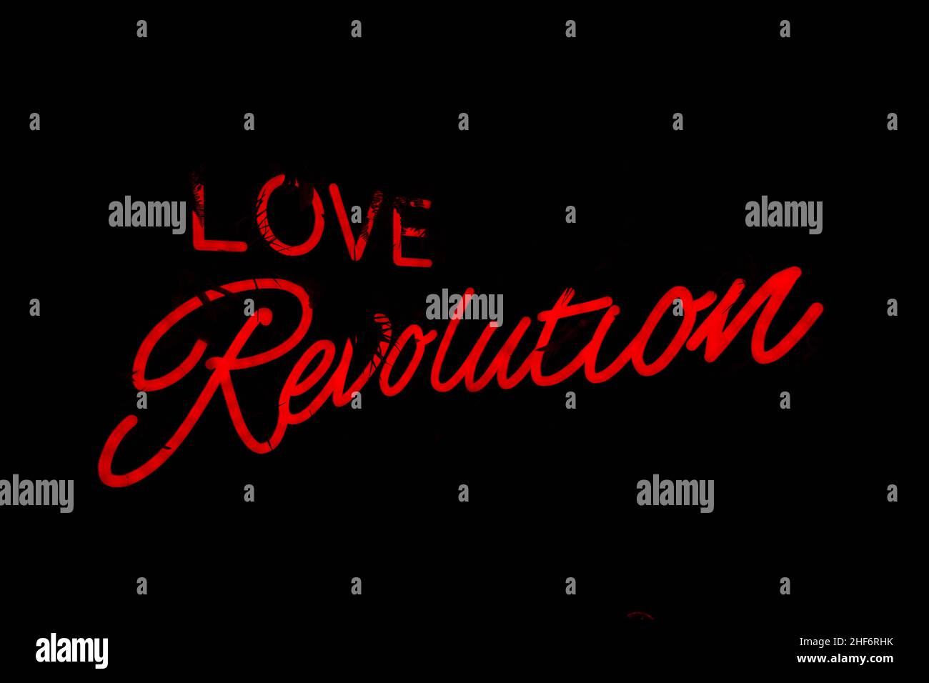 A neon Love Revolution sign in hot pink. Inspiration quote. Cool urban background. Stock Photo