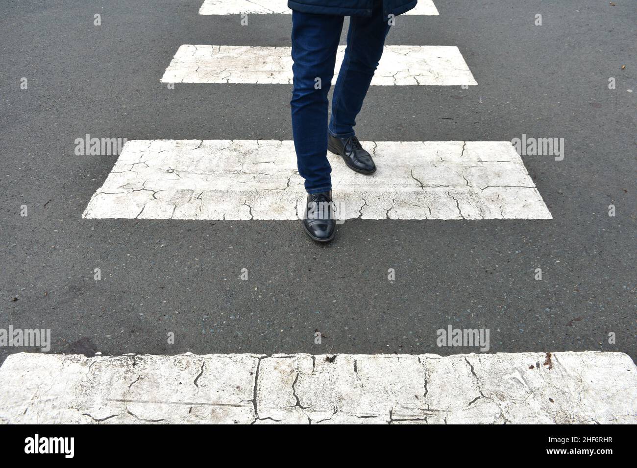 close up of mans feet and legs, walking along a zebra crossing