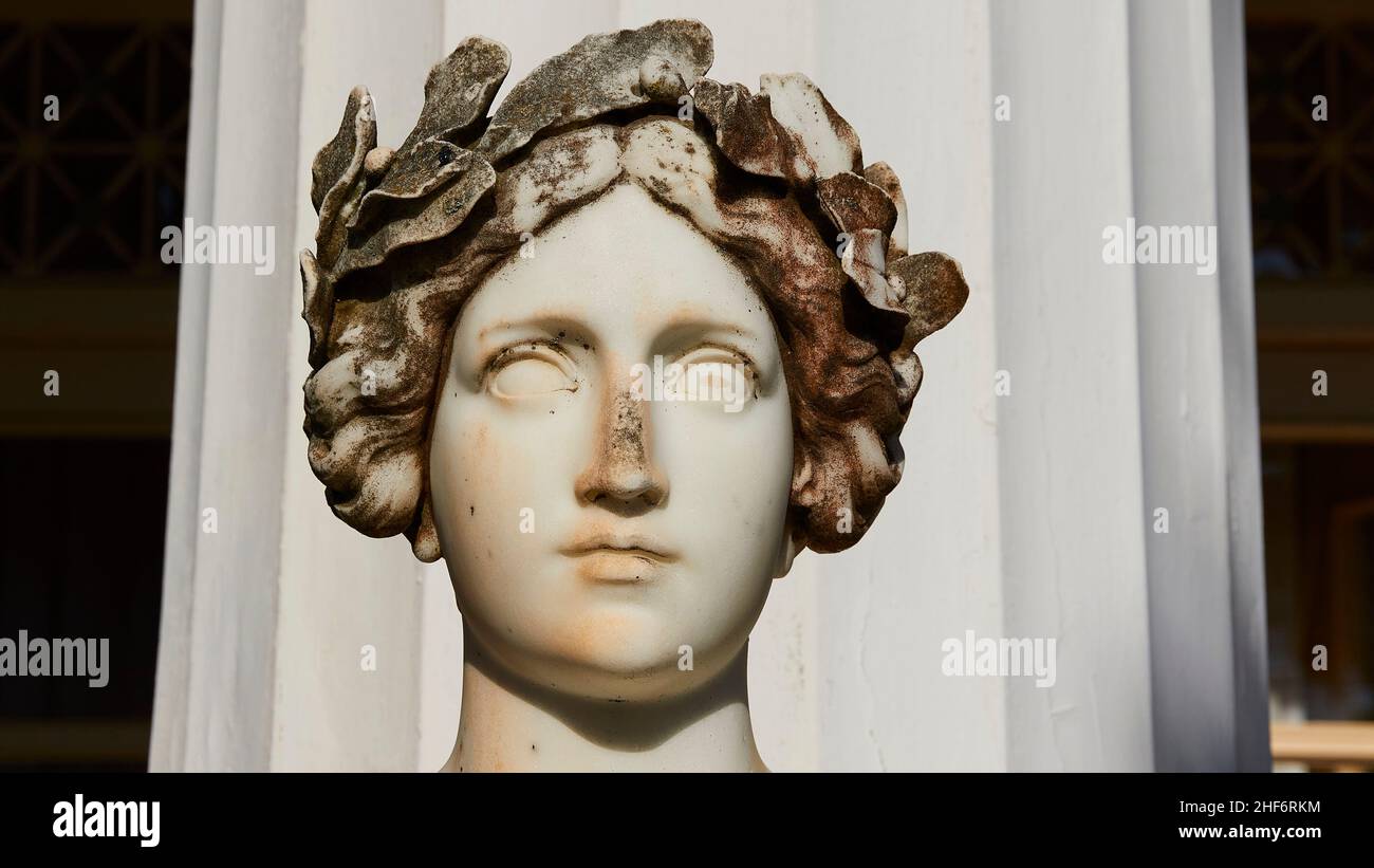 Greece,  Greek islands,  Ionian islands,  Corfu,  Achilleion,  residence of Empress Sissis,  built in 1889,  architecture based on Greek mythology,  terraces,  marble head of one of the nine muses,  in front of a Greek-looking column,  woman wears a kind of olive wreath on her head Stock Photo