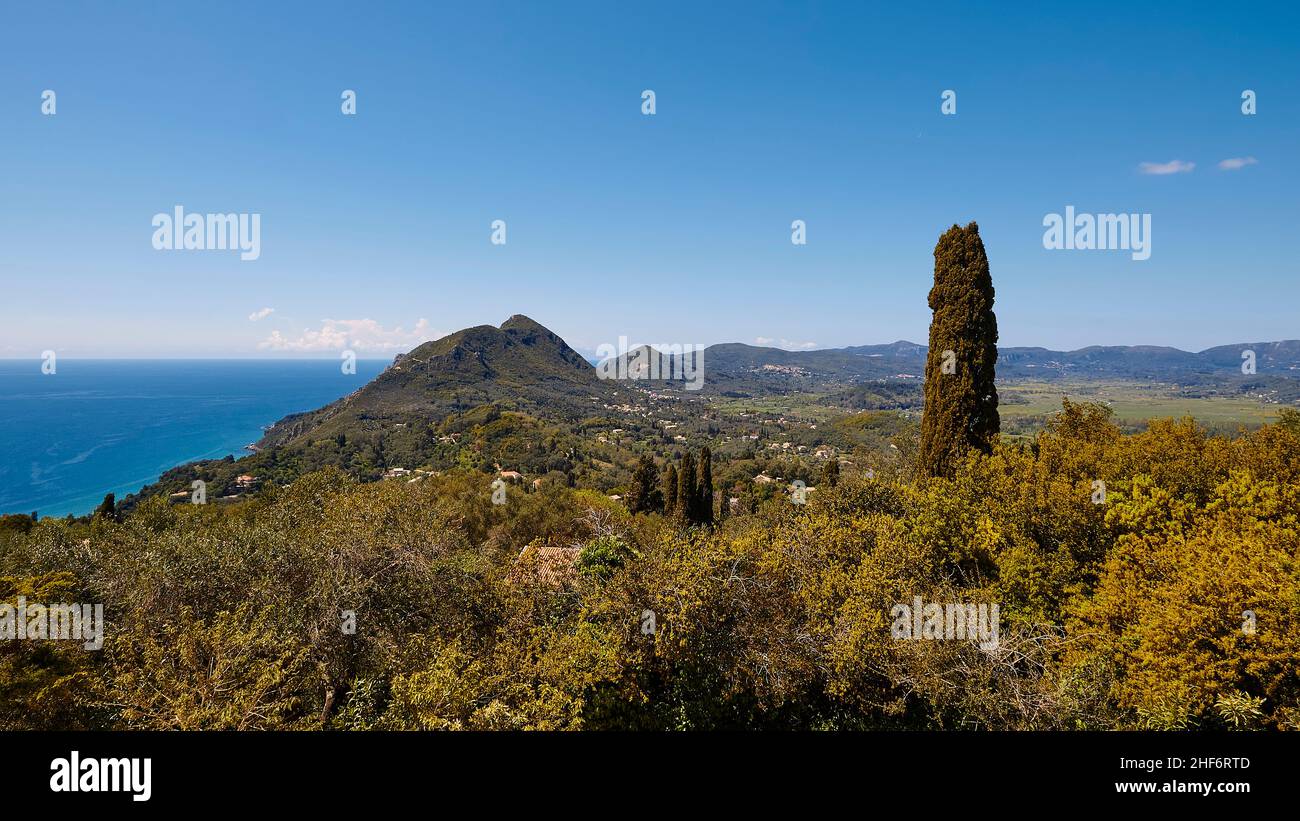 Greece,  Greek Islands,  Ionian Islands,  Corfu,  central north of the island,  viewpoint 'Emperor's Throne',  view of the west and east coast,  view platform,  blue sky,  white clouds,  mountains on the mainland,  view from the viewing platform to the green Interior of Corfu island,  cypress tree,  blue sky Stock Photo