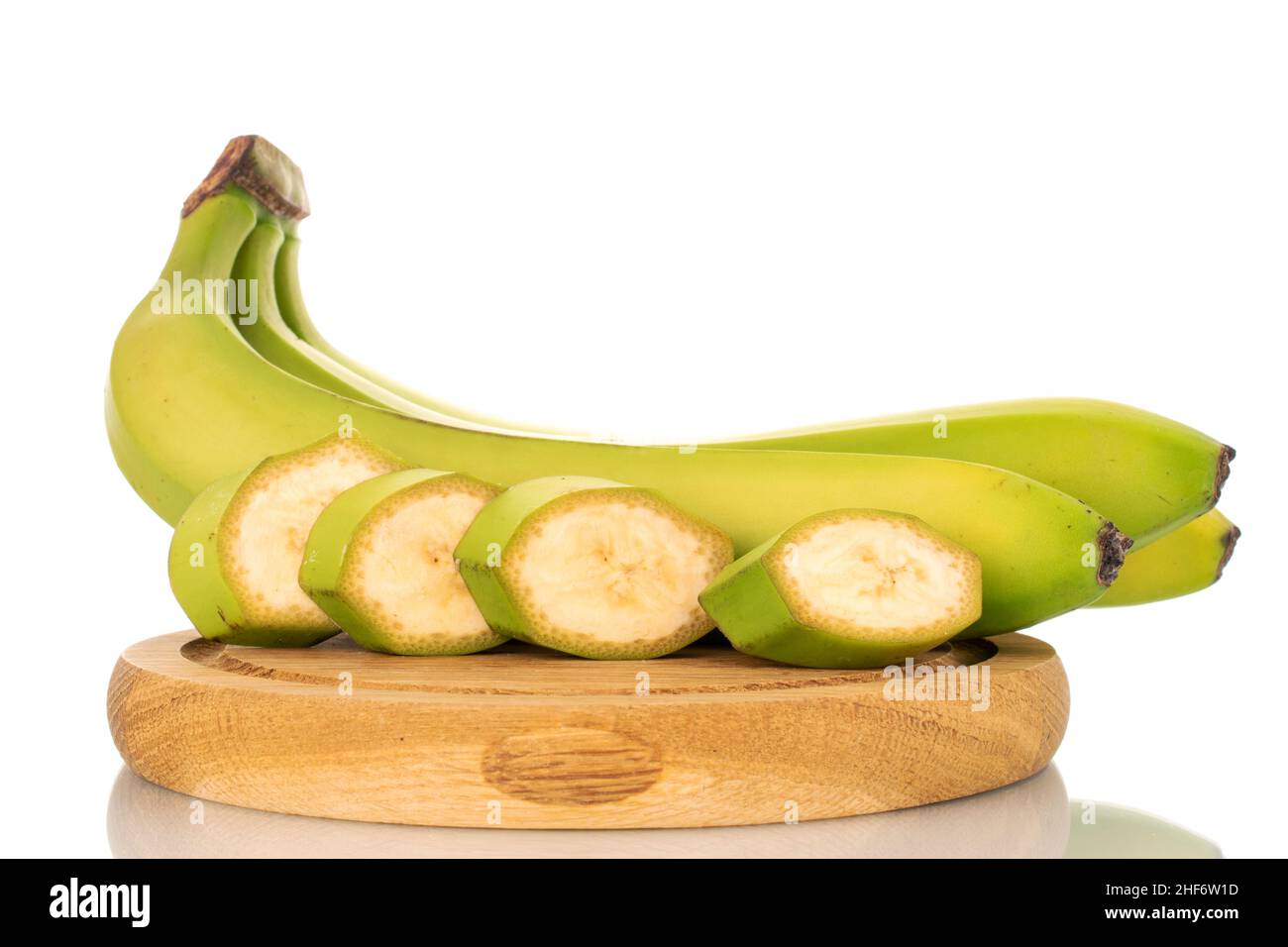 One half and four slices of organic green banana on a cutting board ...