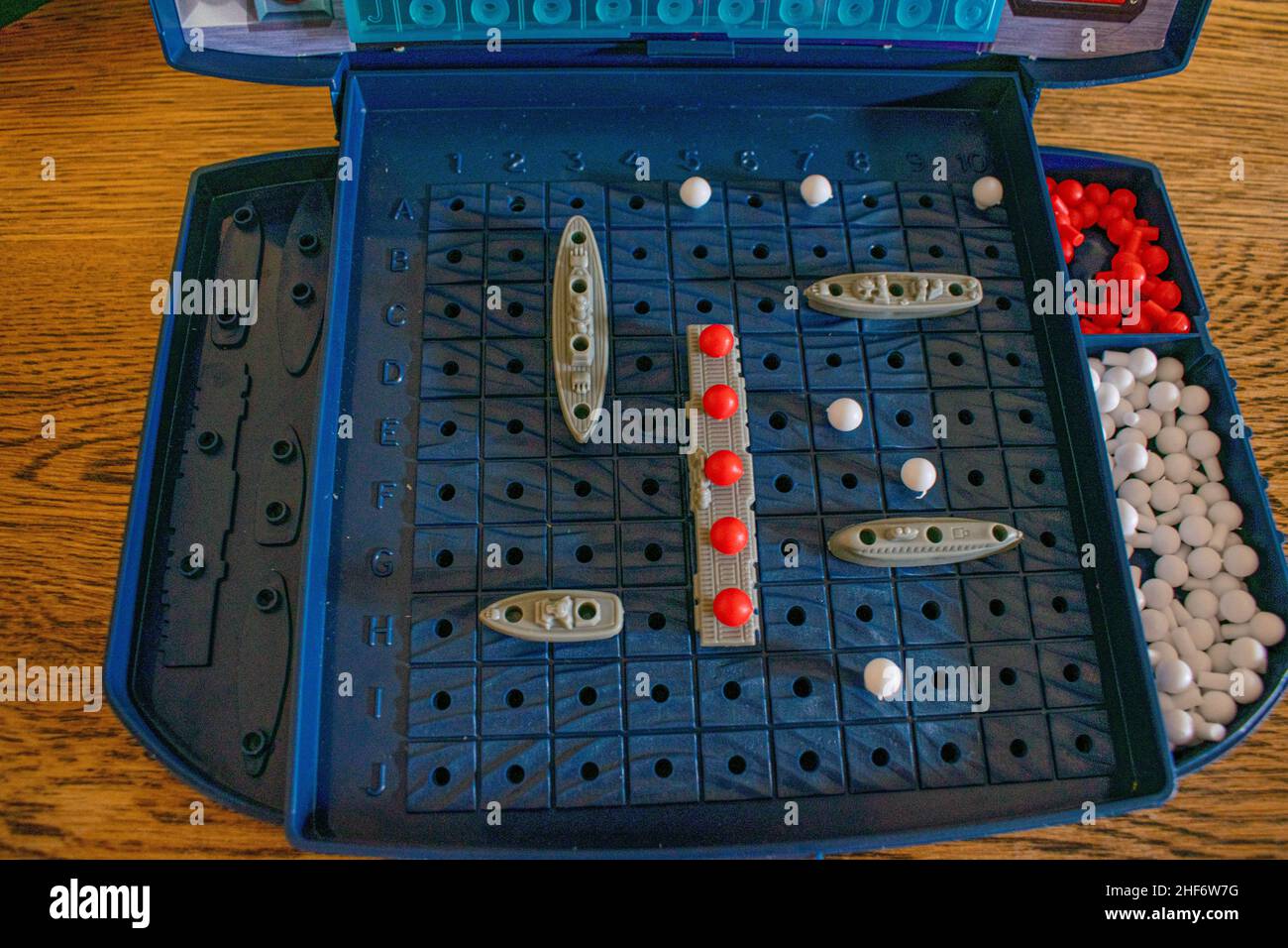 Plastic toy warships and submarines are placed on the playing board representing the ocean. The other player tries to sink your boats in the game Batt Stock Photo