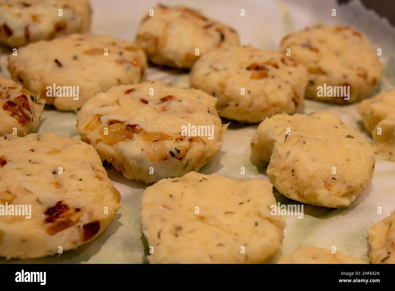 A tray of uncooked round salt cod fishcakes is prepared for frying. The mixture of savory, potato, salt codfish, and butter is shaped into small patties. Stock Photo