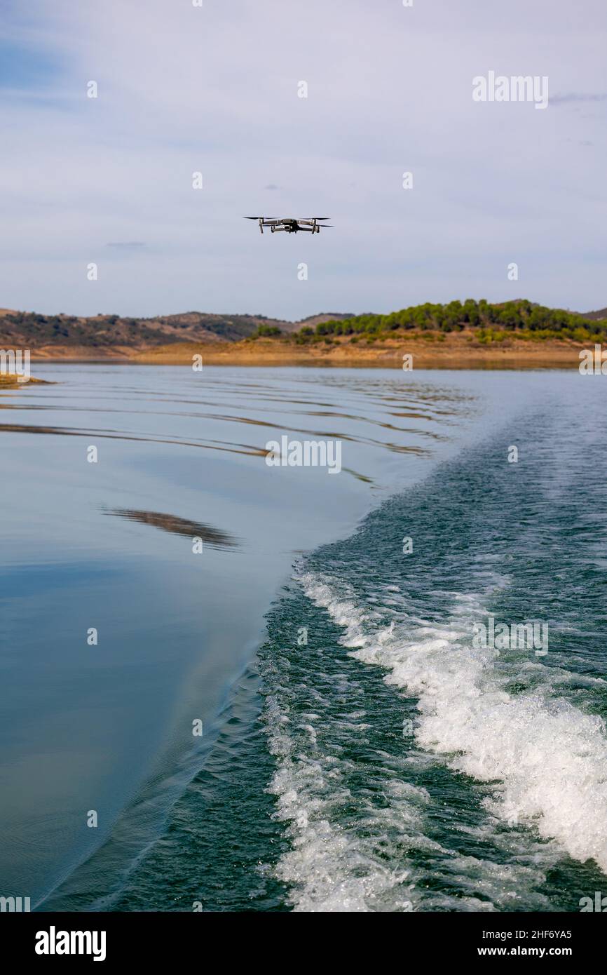 View of drone with camera flying over water with a wave forming in the foreground. Stock Photo