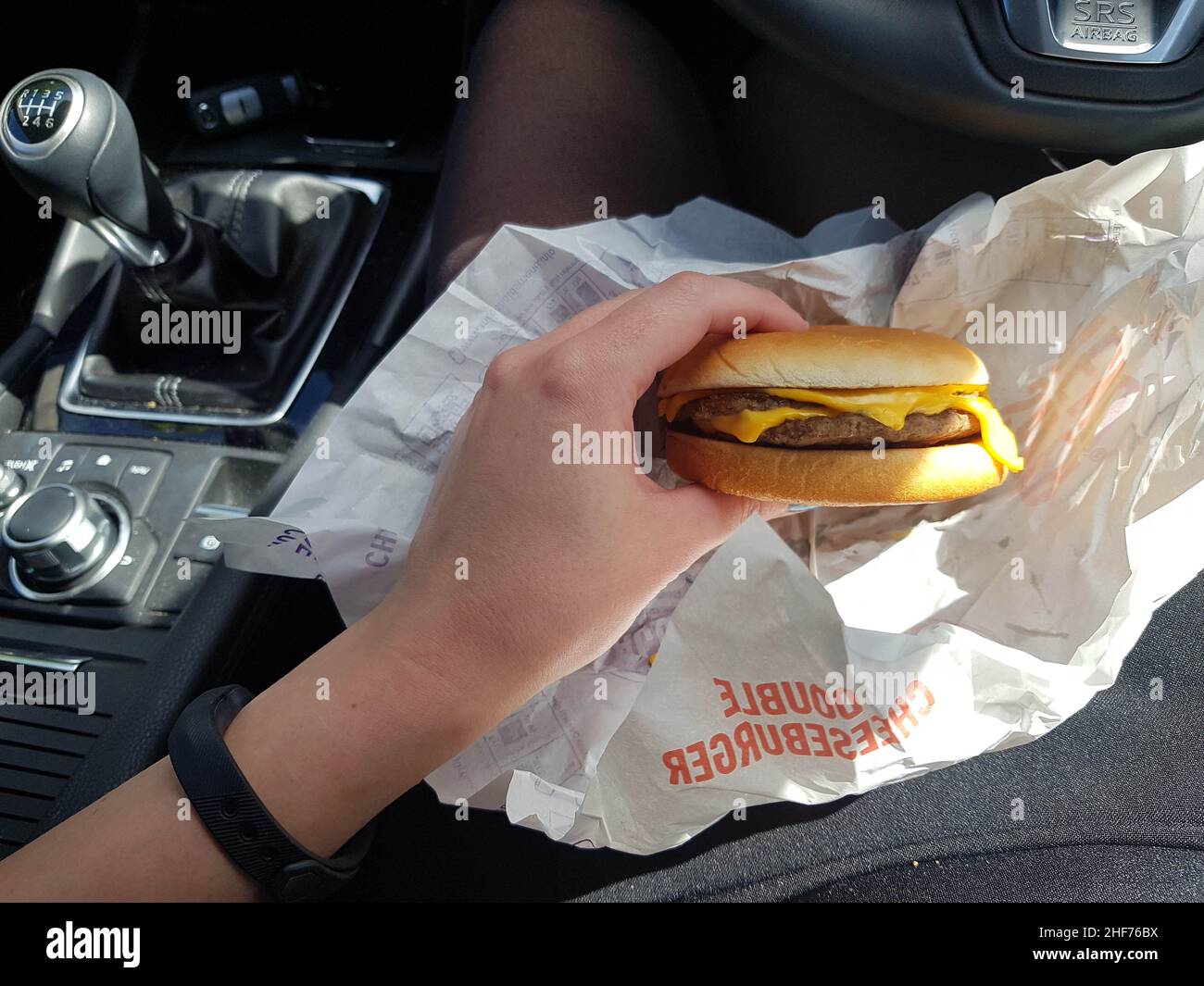 Newcastle Upon Tyne, England - 24th May 2019: Women eating a quick lunch of burger in her car. Busy business lifestyle resorting to drive thru lunch o Stock Photo