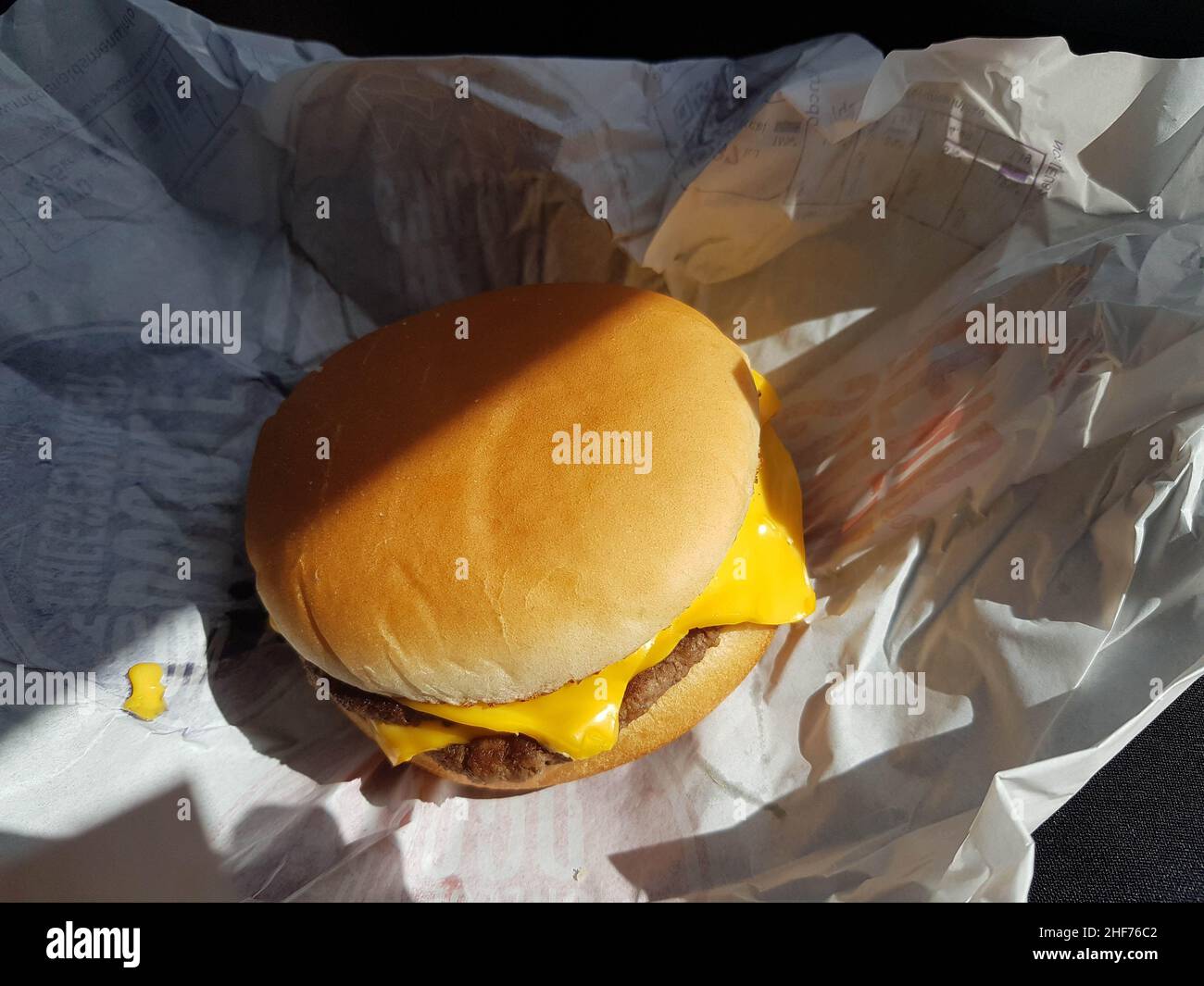 Women eating a quick lunch of burger in her car. Busy business lifestyle resorting to drive thru lunch on the go. Concept busy work life background. M Stock Photo