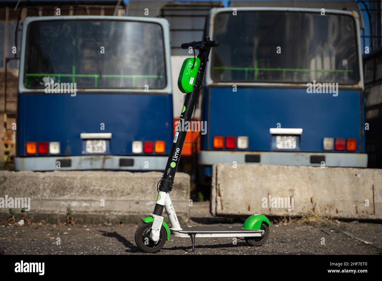 Budapest Transport then and now: Modern electric scooter with old, unused buses in the background. Stock Photo