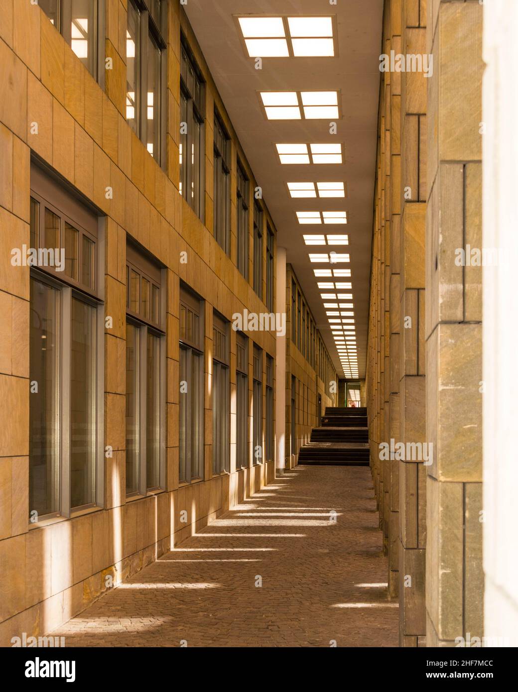Secluded urban street with windows and light reflecting through gaps in walls making symmetrical pattern - background, concept, artistic Stock Photo