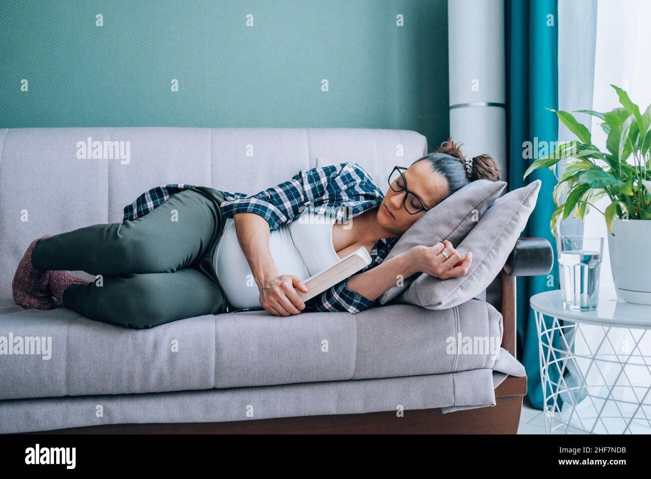 https://c8.alamy.com/comp/2HF7NDB/pregnant-woman-in-eyeglasses-wearing-checkered-shirt-sleep-lying-on-grey-couch-in-living-room-2HF7NDB.jpg