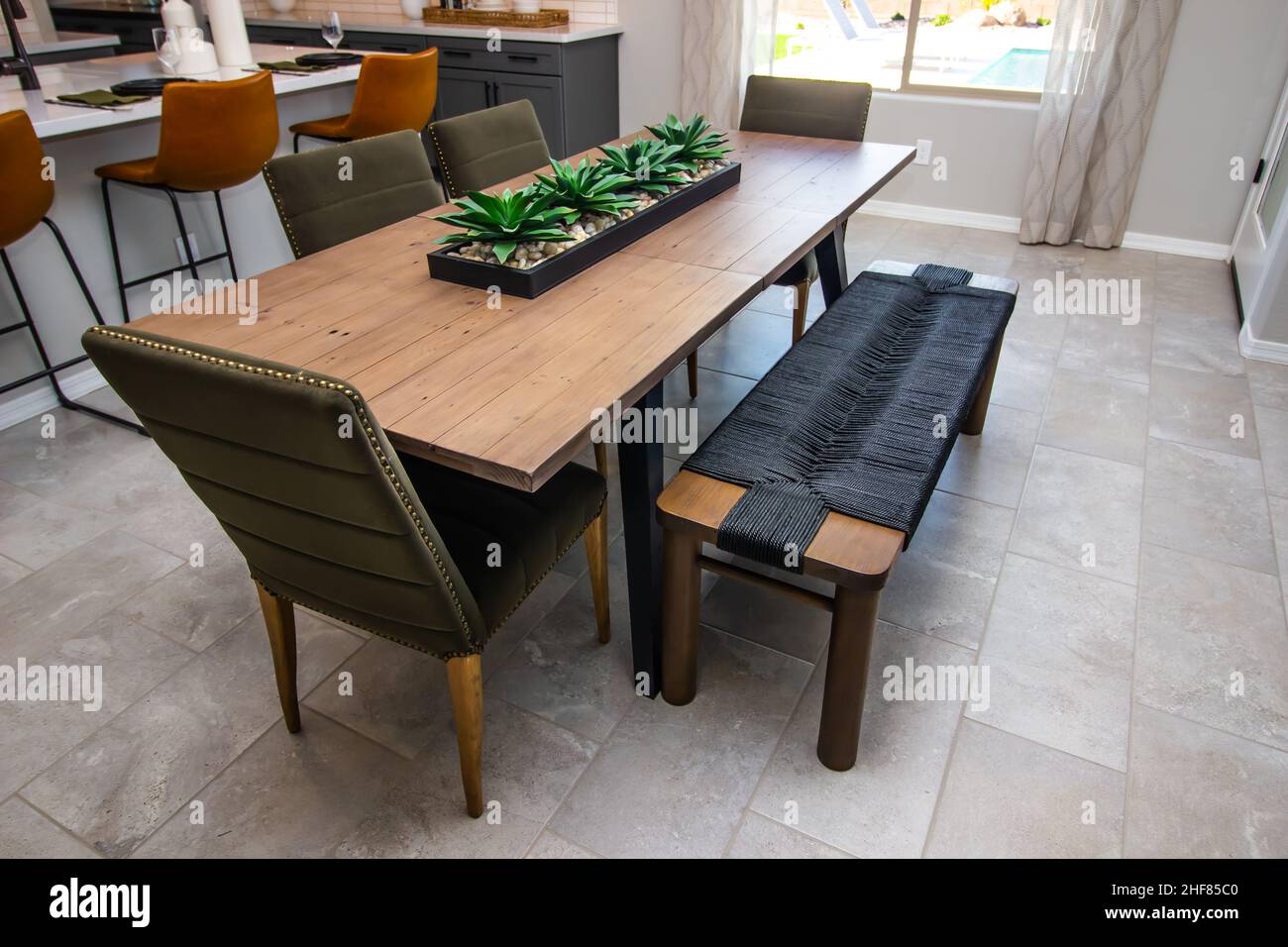 Dining Area Oblong Wooden Table With Centerpiece, High Back Chairs And Sitting Bench Stock Photo