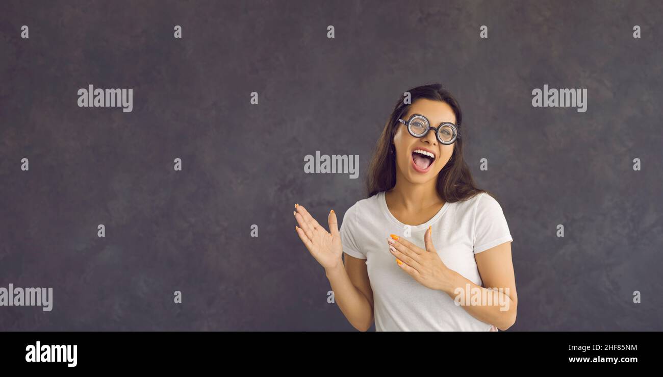 Young funny comic woman isolated on gray studio background pointing at blank copy space aside. Stock Photo