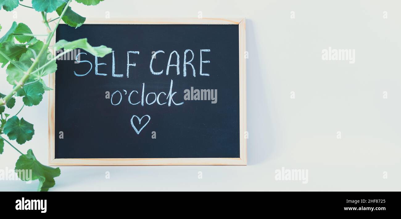 Blackboard with self care o'clock written with chalk with plant to the side and copy space Stock Photo